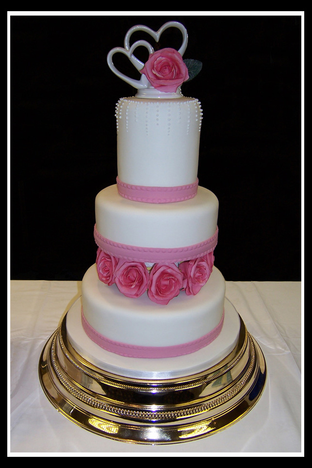 Pink four tier stacked wedding with cake with rose decoration