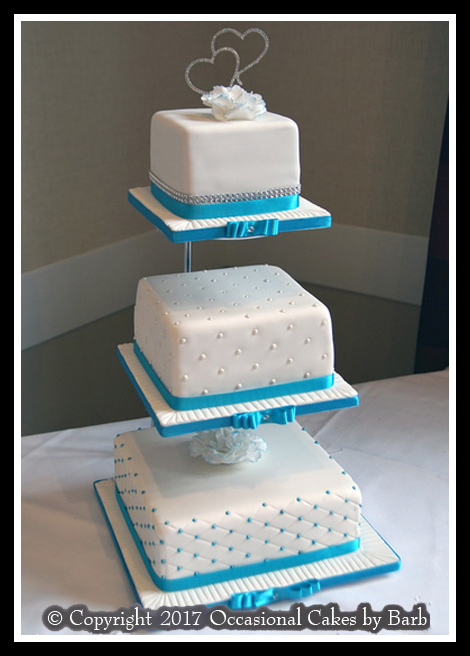 square wedding cake with teal ribbons