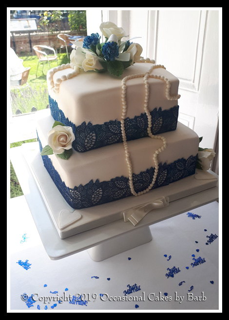 two tier wedding cake with blue edible lace ribbons