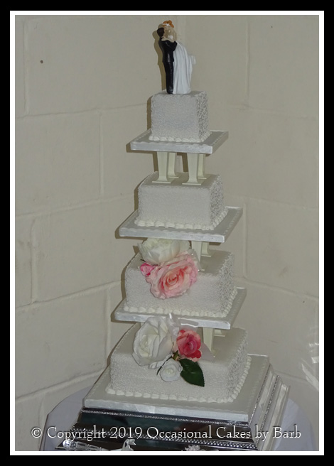 Four tier white wedding cake on pillars